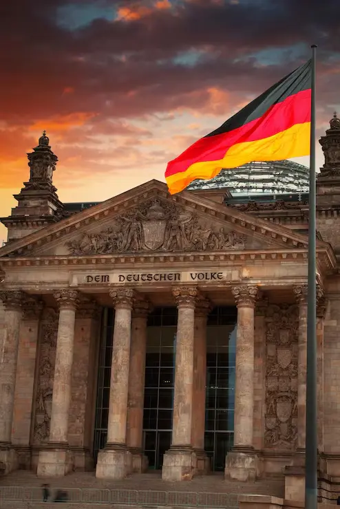 The Reichstag building in Berlin at sunset, the German flag flying above