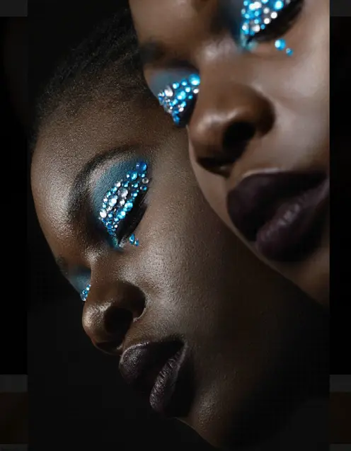 Two women with jewelled eye make-up, faces close together