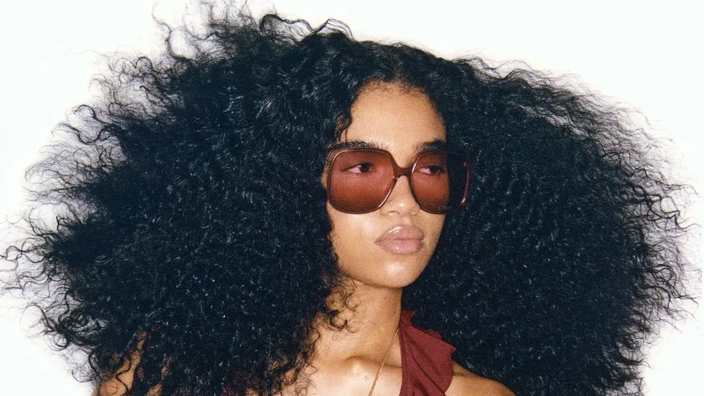 Portrait of a woman with voluminous curls and amber sunglasses